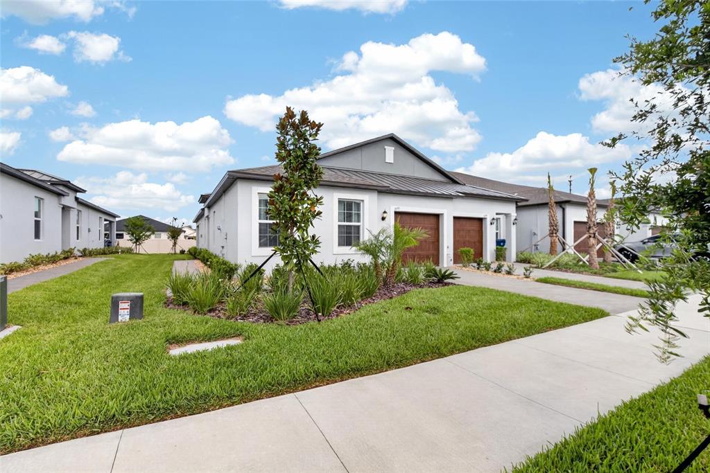 A single-story house with a gray exterior, two garage doors, and a landscaped front yard — 6693 HOMEBOUND WAY, NEW PORT RICHEY, FL