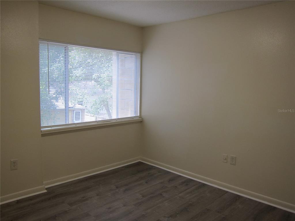 An empty room with beige walls, wood-look flooring, and a large window with blinds — 300 NW 20TH AVENUE UNIT 6, GAINESVILLE, FL