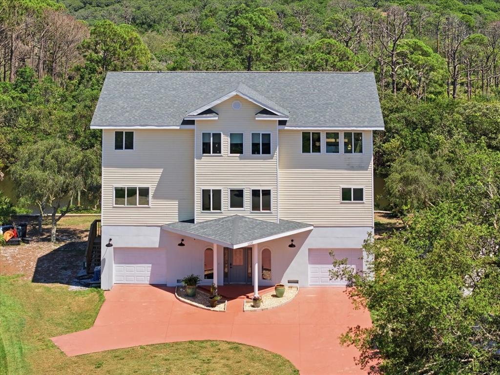 A three-story house with light siding, a gray roof, and two ground-level garages — 1130 S FLORIDA AVENUE, TARPON SPRINGS, FL