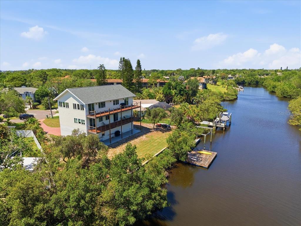 An aerial view shows a multi-story house with wooden decks situated along a narrow waterway — 1130 S FLORIDA AVENUE, TARPON SPRINGS, FL