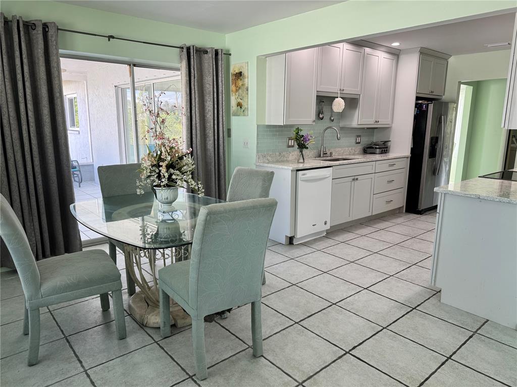 A dining area with a glass table and light green chairs sits beside a kitchen — 1048 PORPOISE ROAD, VENICE, FL