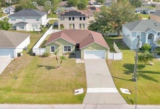 An aerial view shows a single-story green house with a driveway and white fence — 50 SAWFISH COURT, KISSIMMEE, FL