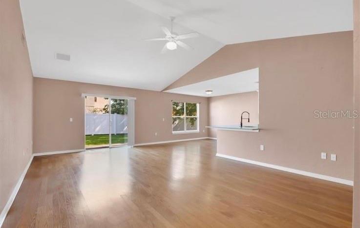 An open-concept living area features vaulted ceilings, hardwood floors, and a kitchen breakfast bar — 50 SAWFISH COURT, KISSIMMEE, FL