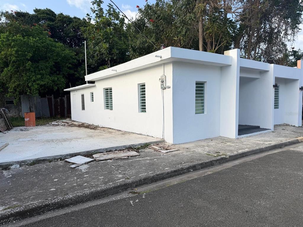 A white, single-story concrete building with louvered windows sits on a corner lot — 122 BADE PEREZ ST., GUAYAMA, PR
