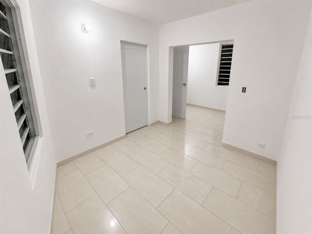 A small, empty room with white walls, light-colored tile flooring, and two interior doors — 122 BADE PEREZ ST., GUAYAMA, PR