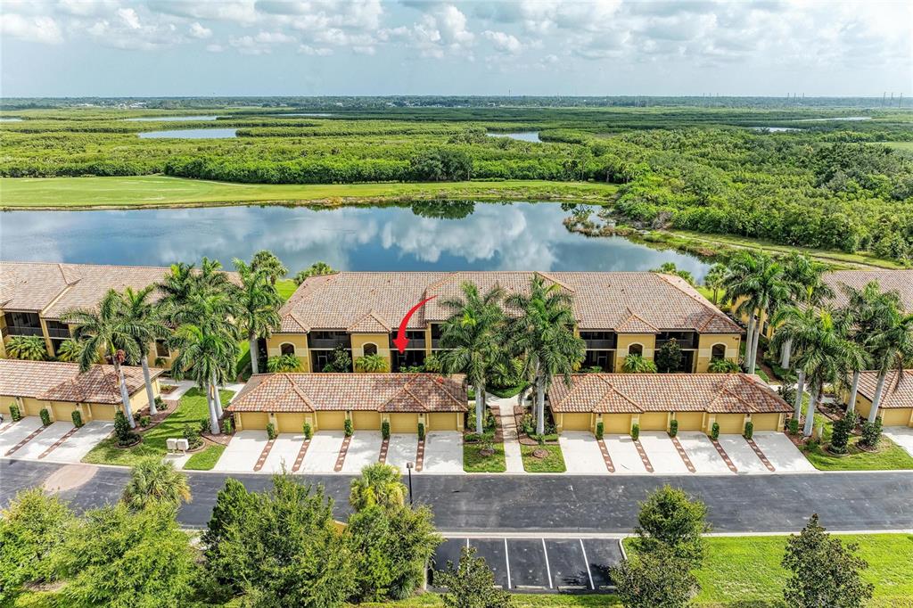 An aerial view shows a multi-story residential building with tile roofs and a red arrow — 7305 RIVER HAMMOCK DRIVE UNIT 102, BRADENTON, FL