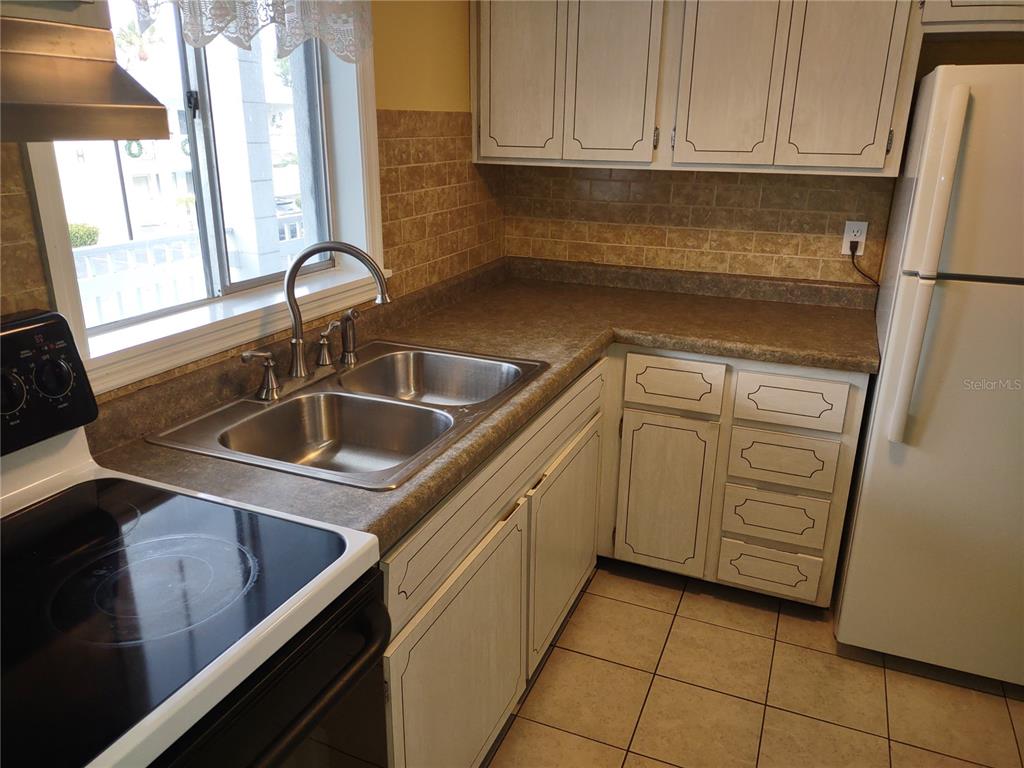 A kitchen features white cabinets, a double sink, brown countertops, and a tile floor — 1566 PLEASANT ROAD UNIT J24, BRADENTON, FL