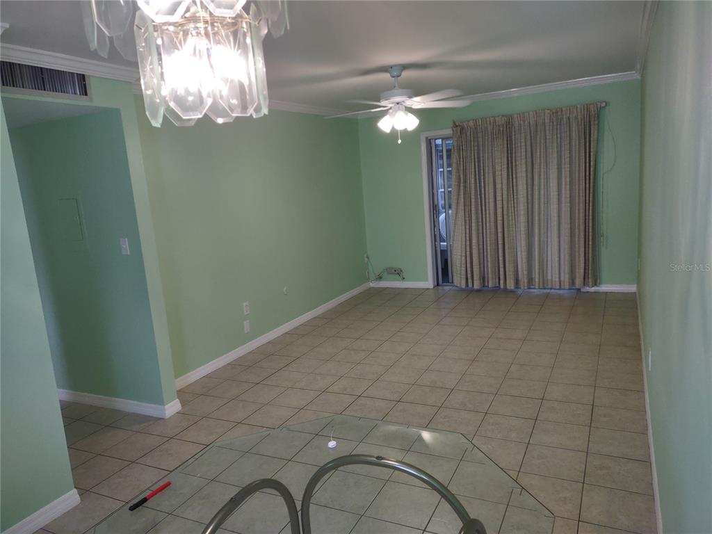A living room with light green walls, tile flooring, a ceiling fan, and sliding glass doors — 1566 PLEASANT ROAD UNIT J24, BRADENTON, FL