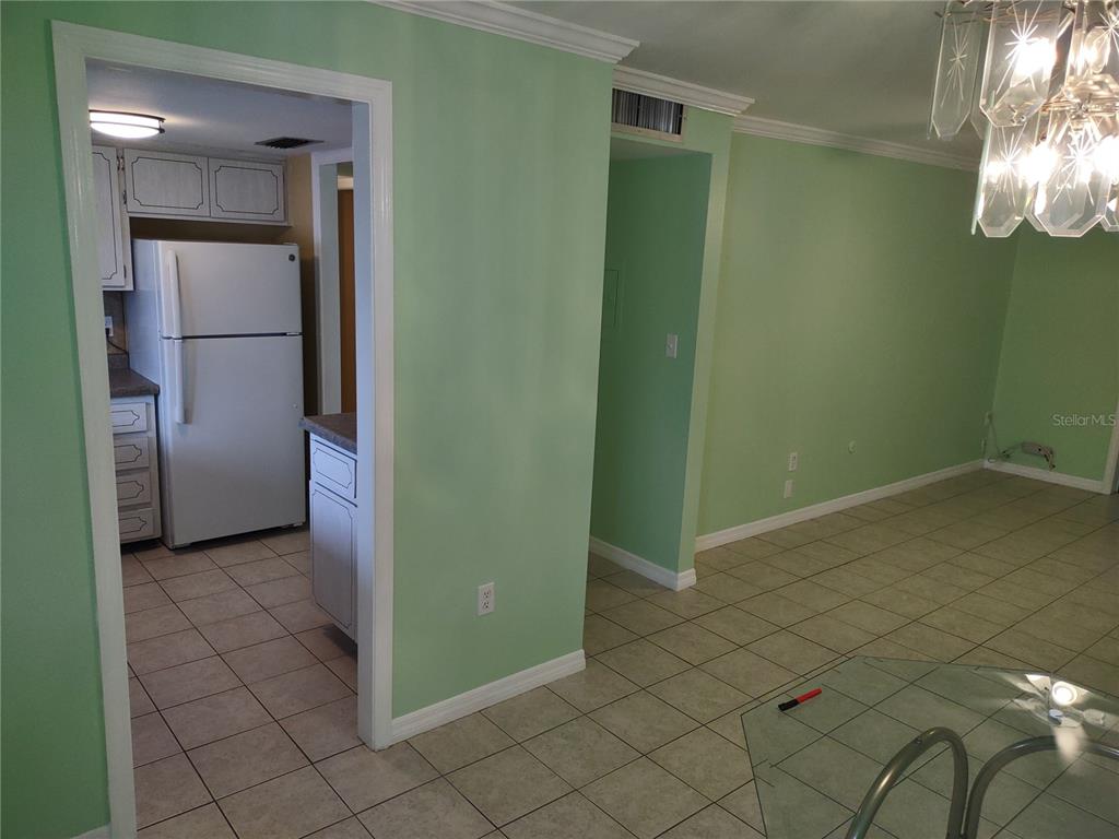 A dining area with light green walls and tile flooring opens into a white kitchen — 1566 PLEASANT ROAD UNIT J24, BRADENTON, FL