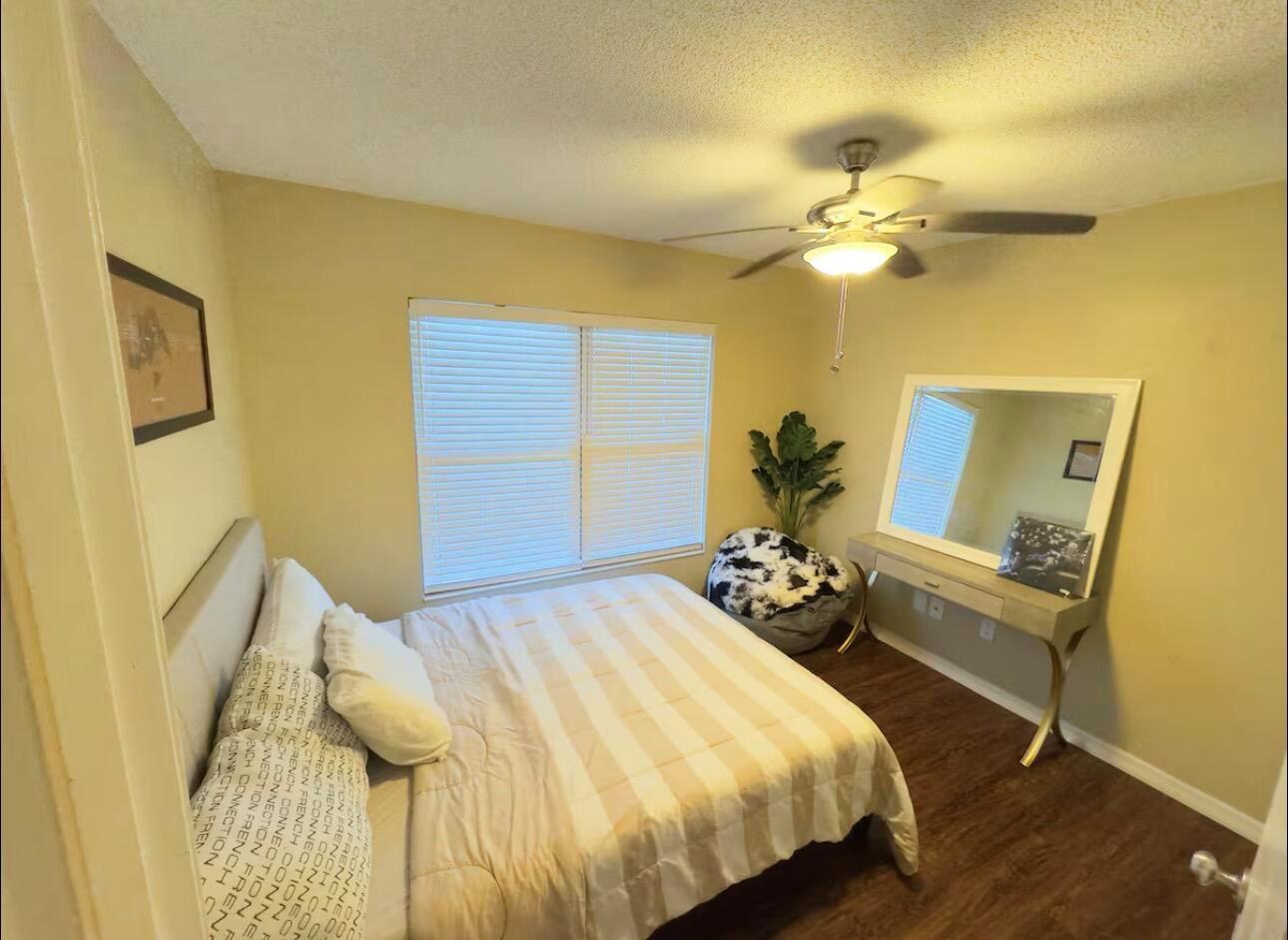 A bedroom features a bed with patterned bedding, a vanity with a mirror, and a ceiling fan — 108 Lacosta Lane # 611, FL 32114, FL