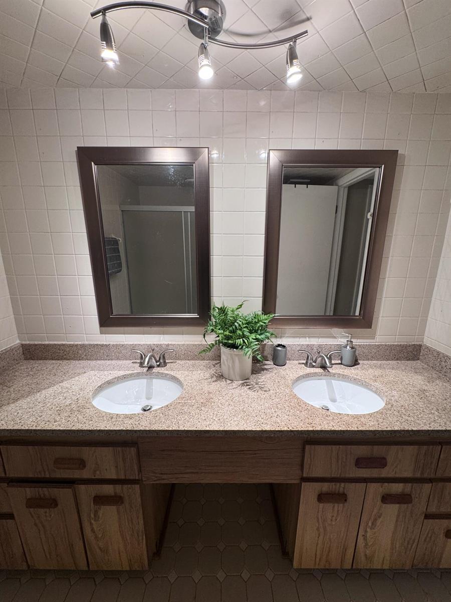 A bathroom vanity features dual sinks, wood cabinets, granite countertops, and two framed mirrors — 108 Lacosta Lane # 611, FL 32114, FL