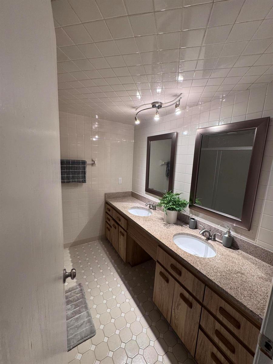 A bathroom features a double vanity with a granite countertop and white tiled walls — 108 Lacosta Lane # 611, FL 32114, FL