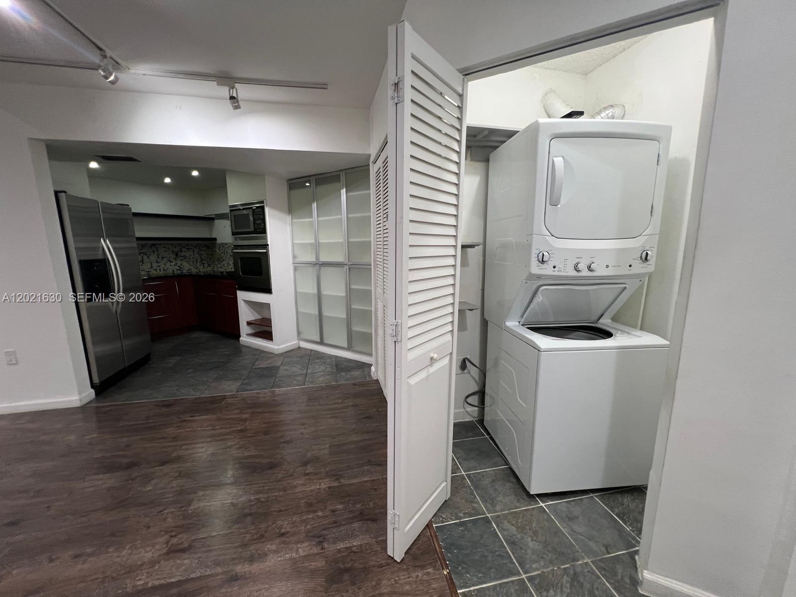 A laundry closet with a stacked washer and dryer sits beside a kitchen area — 9715 Fontainebleau Blvd # E308, Miami FL 33172, MIAMI, FL