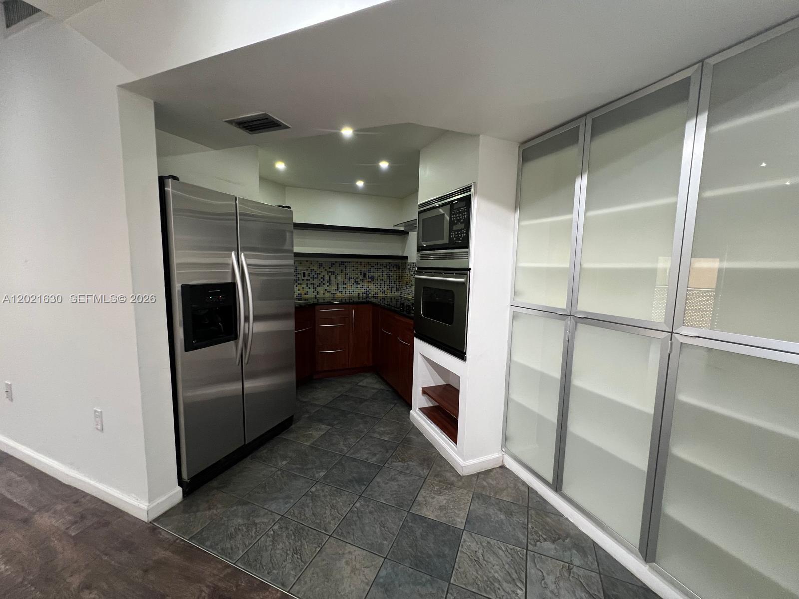 A kitchen features stainless steel appliances, dark wood cabinetry, and a tiled floor — 9715 Fontainebleau Blvd # E308, Miami FL 33172, MIAMI, FL