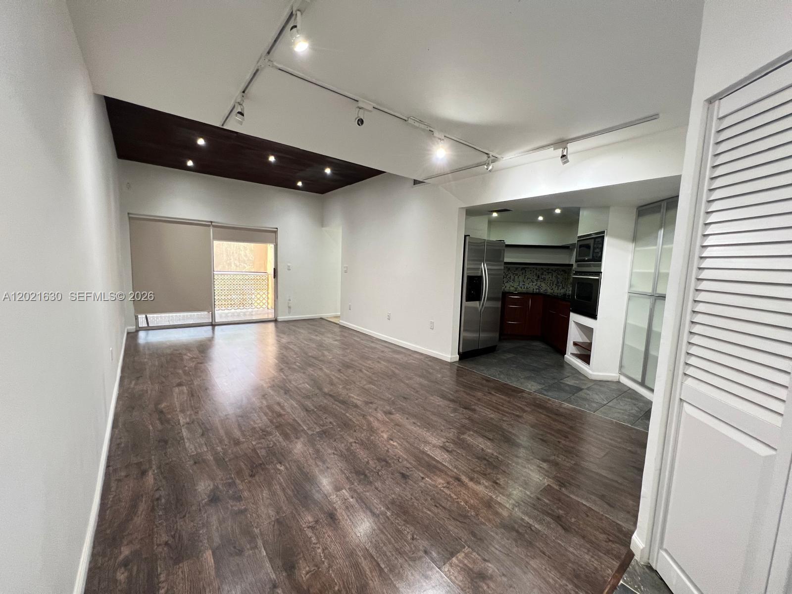 An open living area features dark wood flooring, a recessed wood ceiling, and an adjacent kitchen — 9715 Fontainebleau Blvd # E308, Miami FL 33172, MIAMI, FL