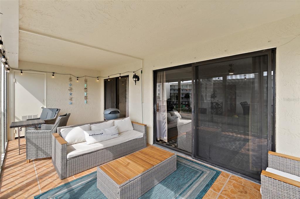 A covered patio features wicker furniture, a wooden coffee table, and a sliding glass door — 190 ESCAMBIA LANE UNIT 305, COCOA BEACH, FL