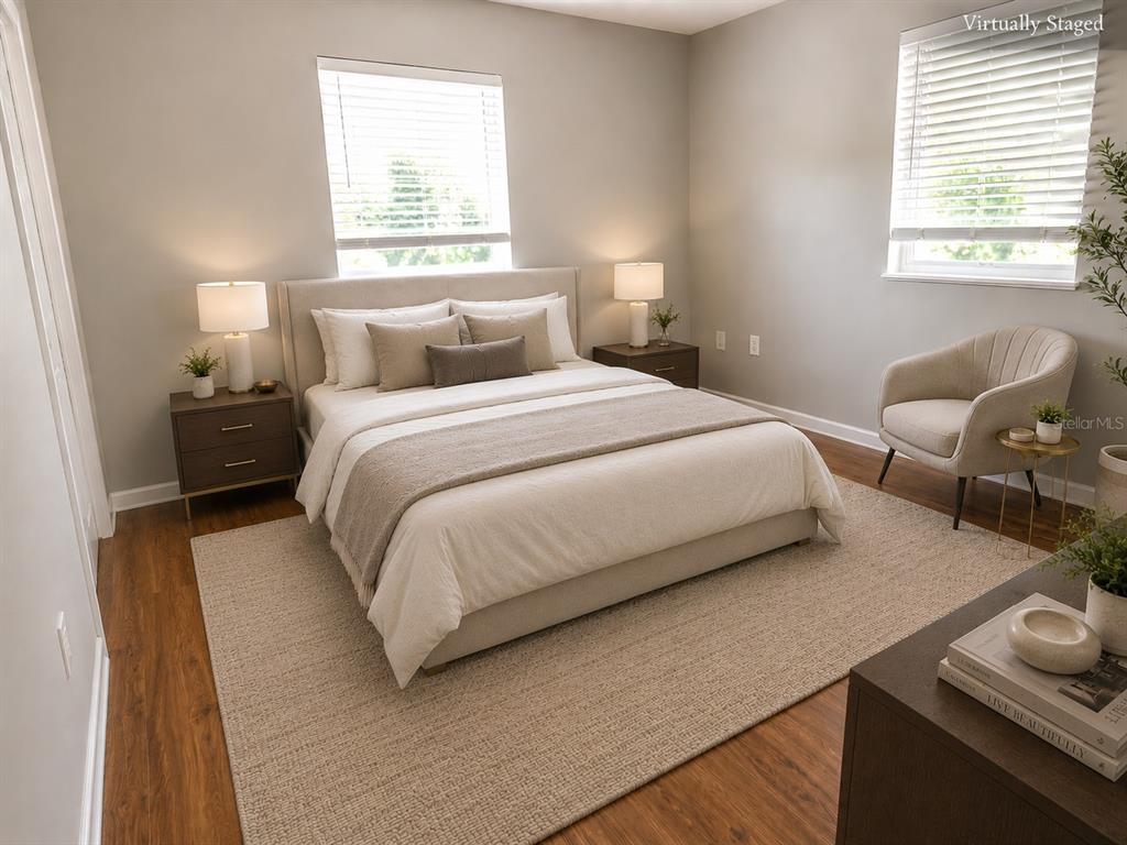 A virtually staged bedroom features a bed, two nightstands, an armchair, and wood-look flooring — 7708 2ND AVENUE W, BRADENTON, FL
