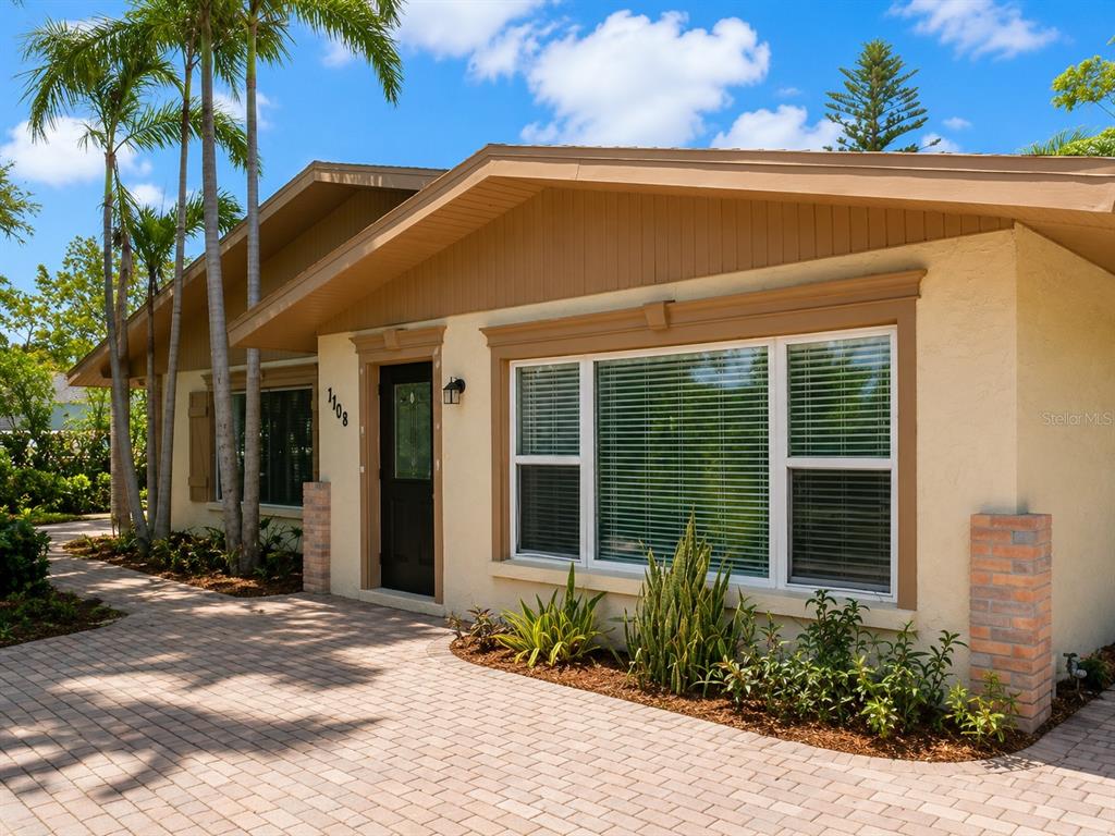 A single-story house with a beige stucco exterior, brown trim, and a brick-paved driveway — 7708 2ND AVENUE W, BRADENTON, FL