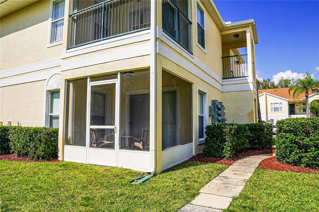 A two-story building features a ground-level screened-in patio and an upper-level balcony — 8812 GRAND PALMS CIRCLE UNIT A, KISSIMMEE, FL