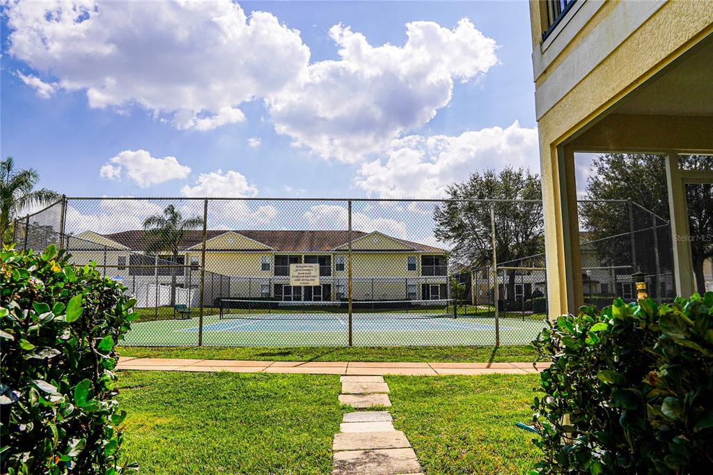 A tennis court is enclosed by a chain-link fence in front of a residential building — 8812 GRAND PALMS CIRCLE UNIT A, KISSIMMEE, FL