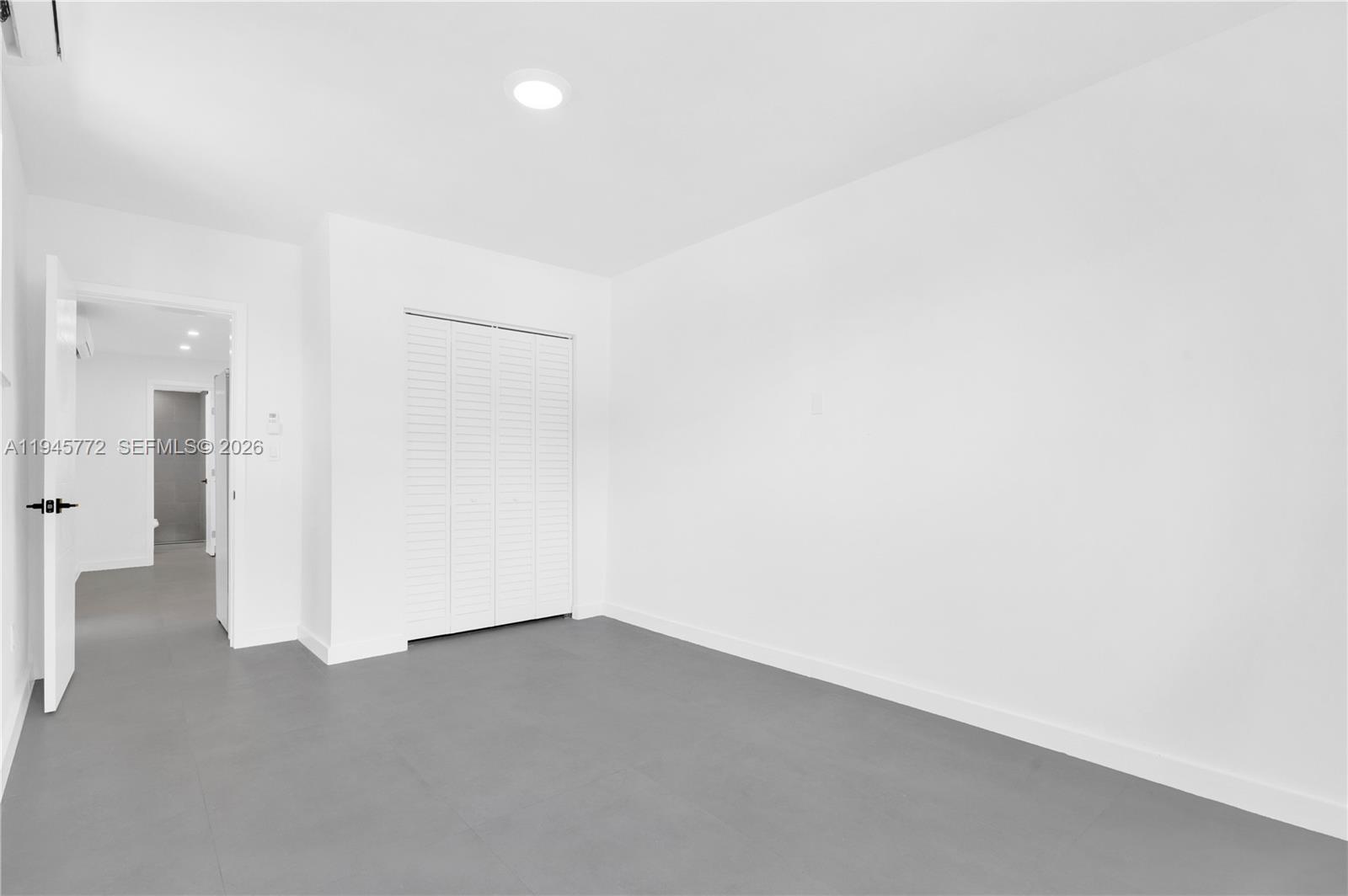An empty room features white walls, gray flooring, and a white louvered closet door — 3040 NW 93rd St # A, Miami FL 33147, MIAMI, FL