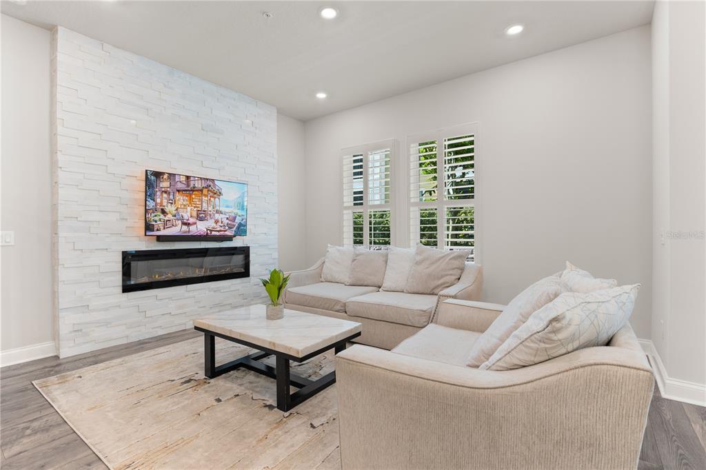 A living room features a white stone fireplace wall, a television, and light-colored furniture — 934 WILD DATE LANE, LAKE MARY, FL