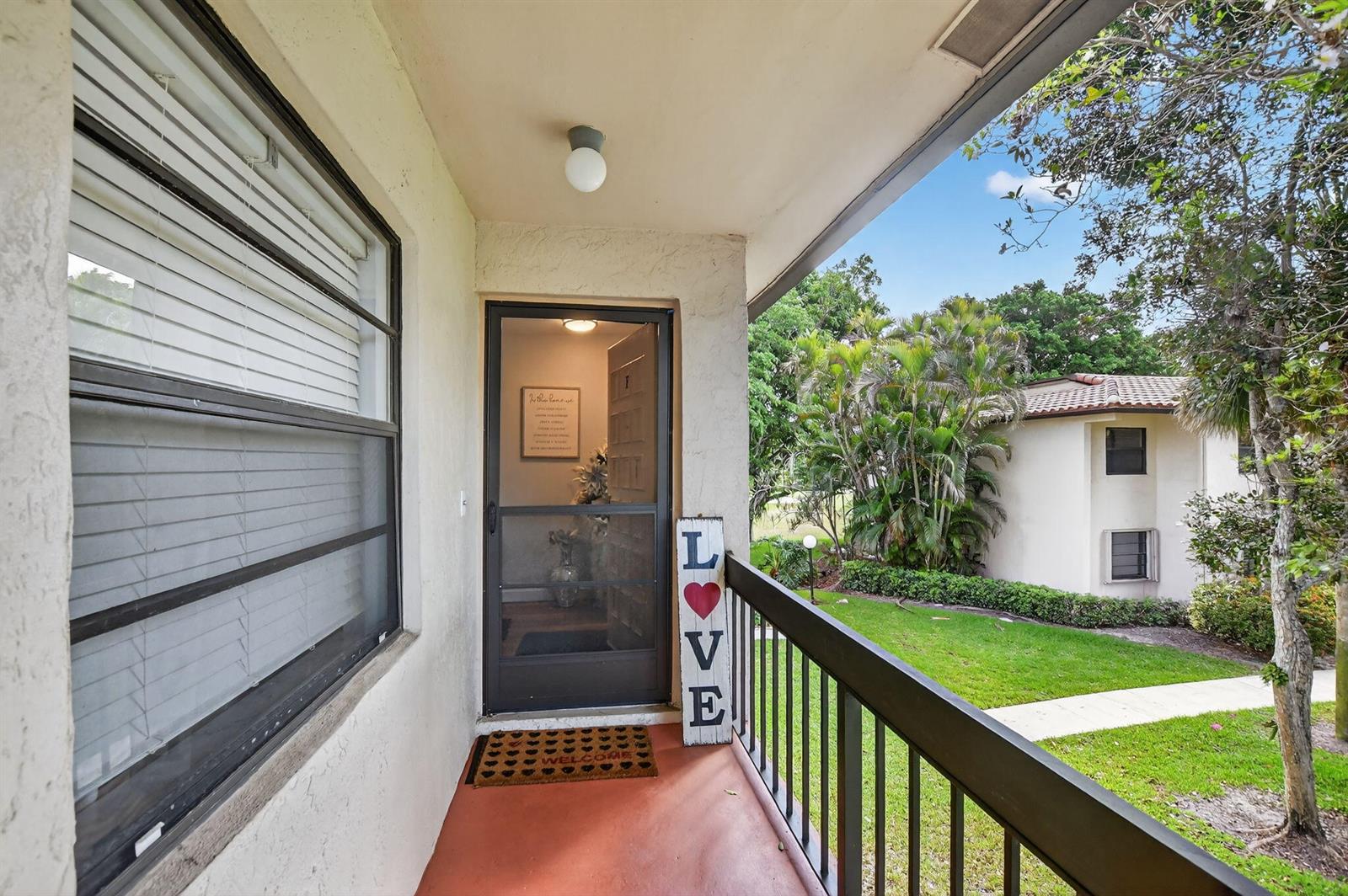 A covered balcony features a screen door, a "LOVE" sign, and a view of a lawn — 21501 Juego Circle # F, Boca Raton FL 33433, BOCA RATON, FL