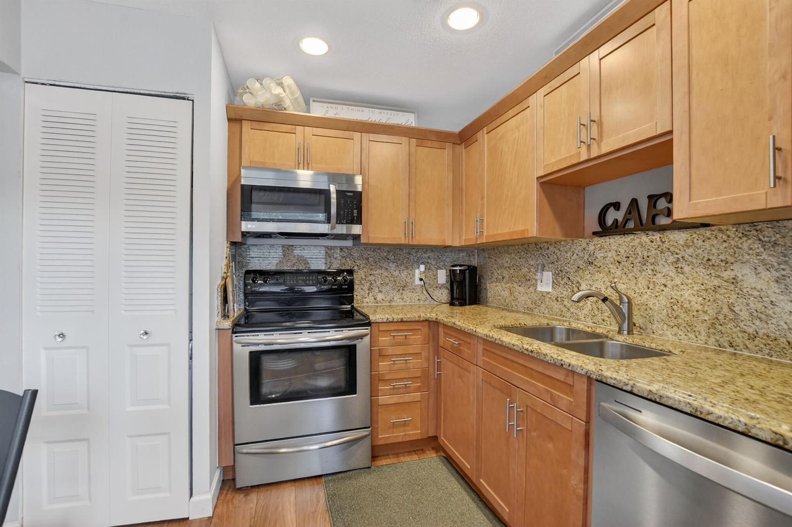 A kitchen features light wood cabinets, granite countertops, and stainless steel appliances — 21501 Juego Circle # F, Boca Raton FL 33433, BOCA RATON, FL