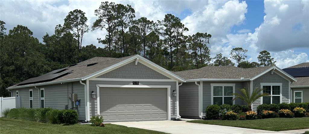 A single-story house with gray siding, a two-car garage, and solar panels on the roof — 5710 ALENLON WAY, MOUNT DORA, FL