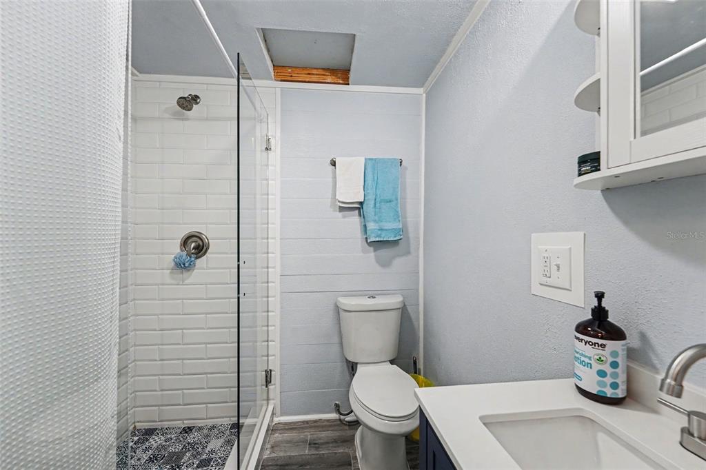 A bathroom features a glass-enclosed shower, a white toilet, and a vanity with a sink — 6251 12TH AVE S, GULFPORT, FL