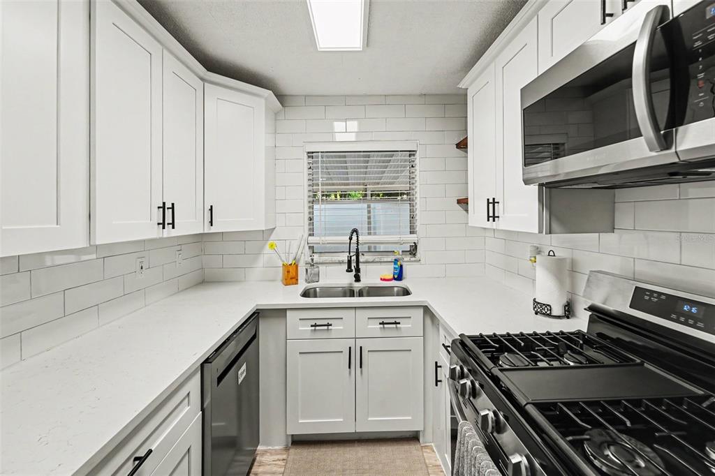 A kitchen features white shaker cabinets, white countertops, a subway tile backsplash, and stainless appliances — 6251 12TH AVE S, GULFPORT, FL