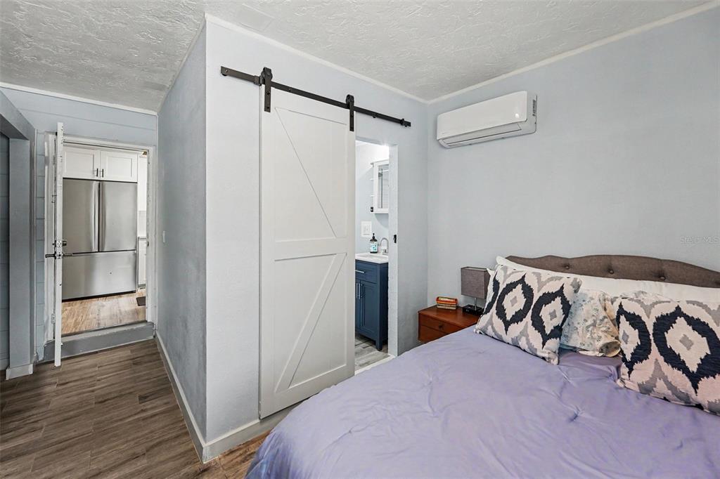 A bedroom with a purple bed, a sliding barn door, and a wall-mounted air conditioner — 6251 12TH AVE S, GULFPORT, FL