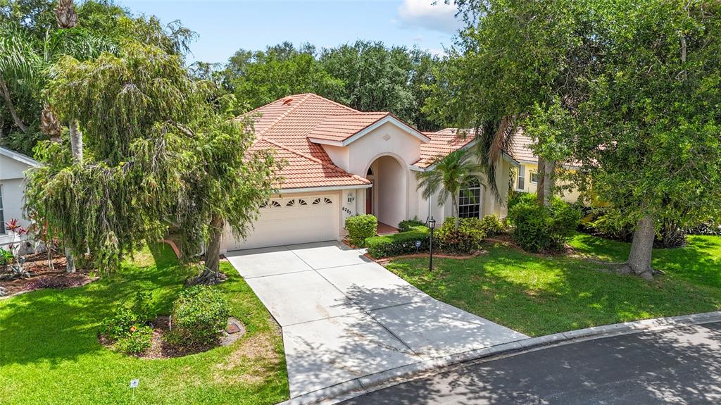 A single-story house with a tiled roof, garage, and arched entryway sits on a lawn — 6223 DONNINGTON COURT, SARASOTA, FL