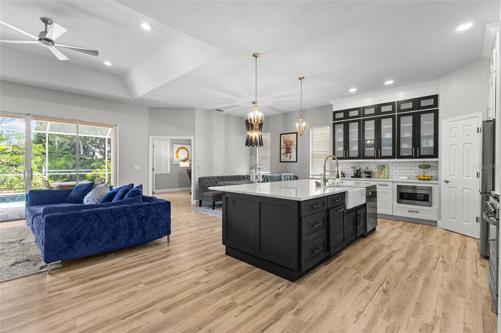 An open-concept kitchen and living area features a large dark island, white cabinets, and flooring — 6223 DONNINGTON COURT, SARASOTA, FL