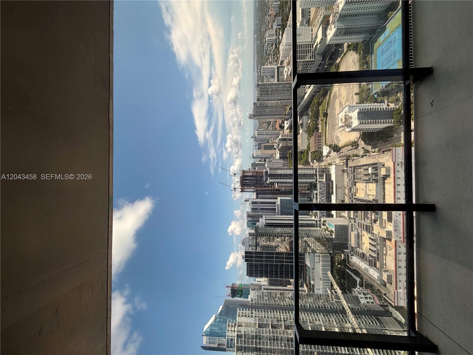 A high-rise balcony overlooks a dense urban cityscape with multiple skyscrapers and construction cranes — 20 NE 11th St # 5103, Miami FL 33132, MIAMI, FL