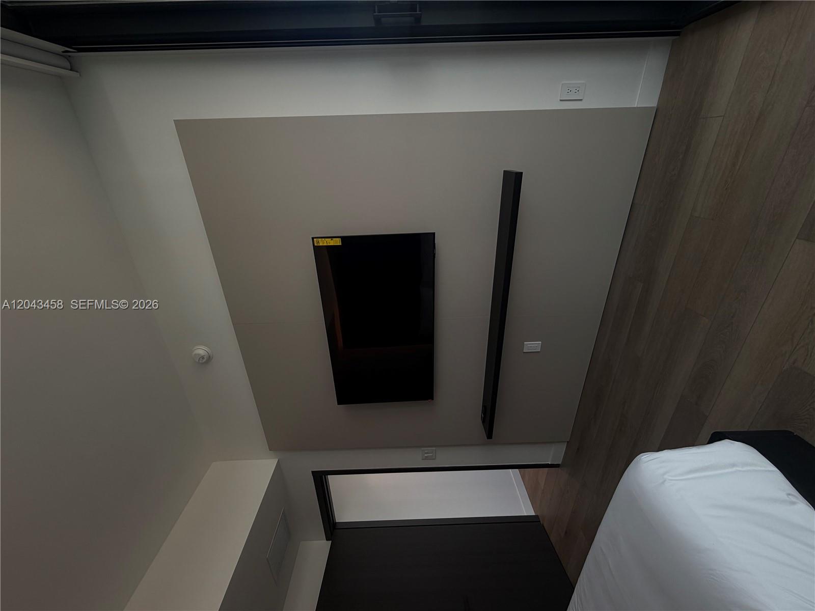 A bedroom features a wall-mounted television and a vertical light fixture on a beige panel — 20 NE 11th St # 5103, Miami FL 33132, MIAMI, FL
