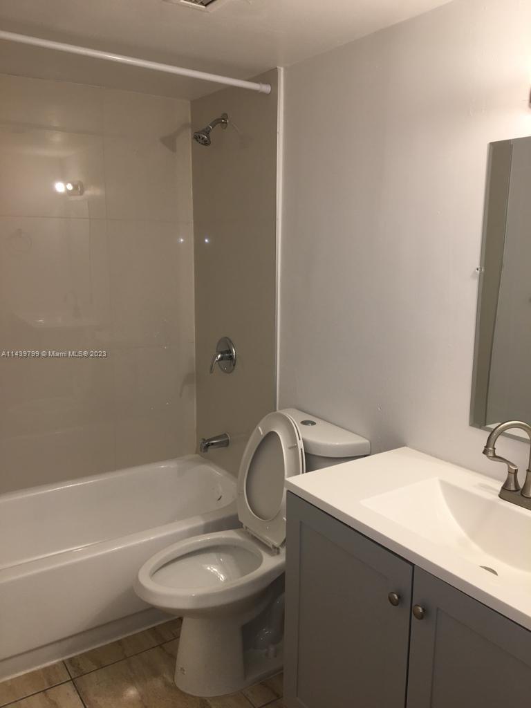 A bathroom features a white bathtub, a toilet, and a gray vanity with a sink — 498 NW 165th St Rd # D205, Miami FL 33169, MIAMI, FL