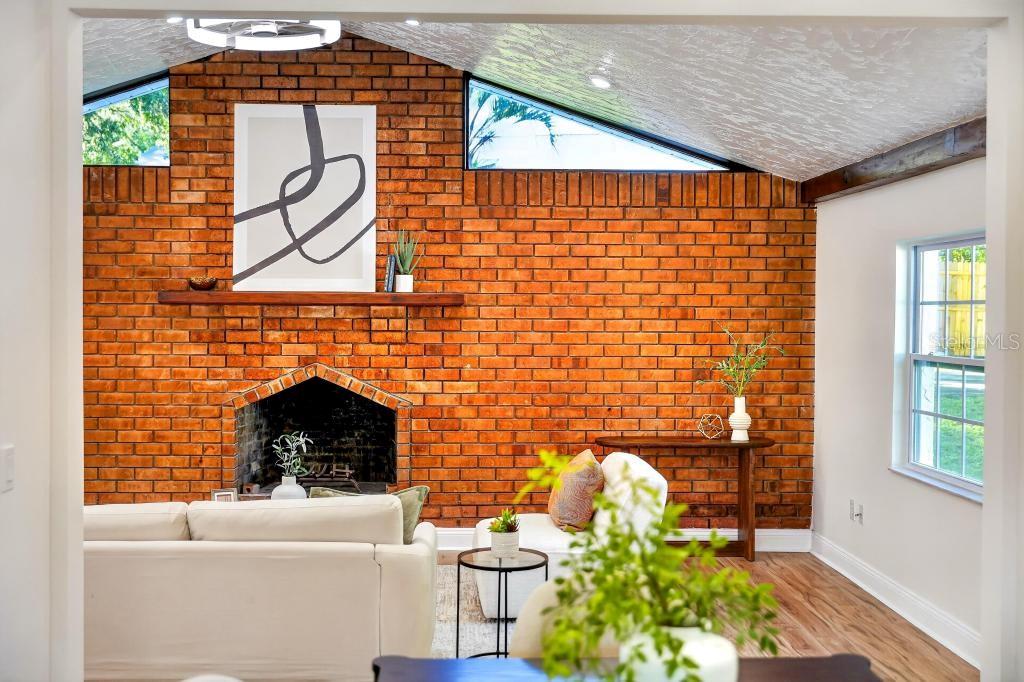 A living room features a large brick fireplace wall, vaulted ceilings, and light wood flooring — 7126 CROOKED LAKE TRAIL, ORLANDO, FL