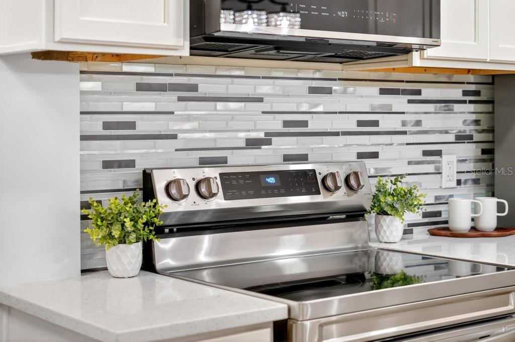 A stainless steel stove sits against a kitchen backsplash with horizontal gray and white tiles — 7126 CROOKED LAKE TRAIL, ORLANDO, FL