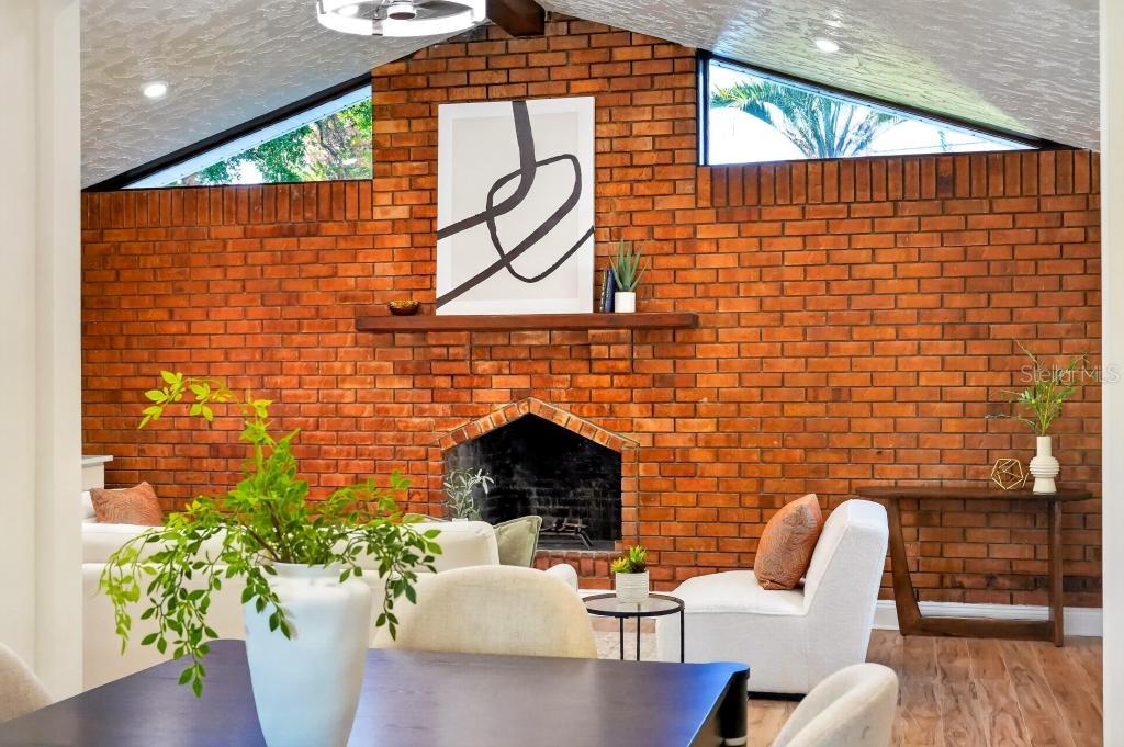 A living room features a large brick fireplace, vaulted ceilings, and modern white furniture — 7126 CROOKED LAKE TRAIL, ORLANDO, FL