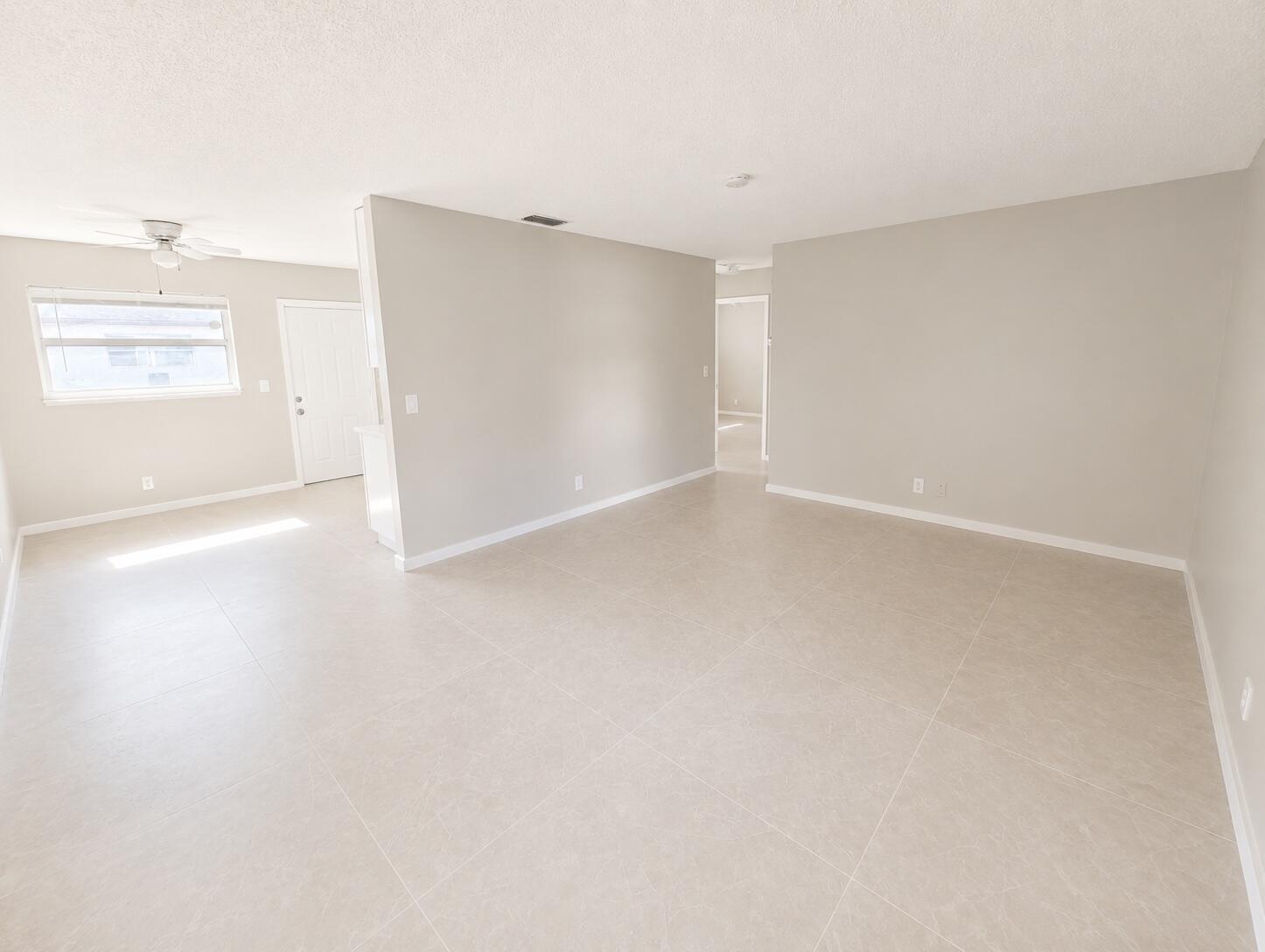 An empty living area features light-colored tile flooring, neutral walls, and a ceiling fan — 1794 Juno Road # 2, North Palm Beach FL 33408, NORTH PALM BEACH, FL