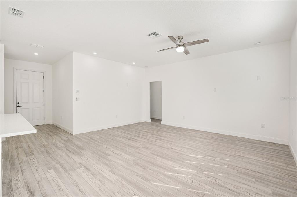 A bright, empty room features white walls, light wood-look flooring, and a ceiling fan — 7834 TERN DRIVE, ORLANDO, FL