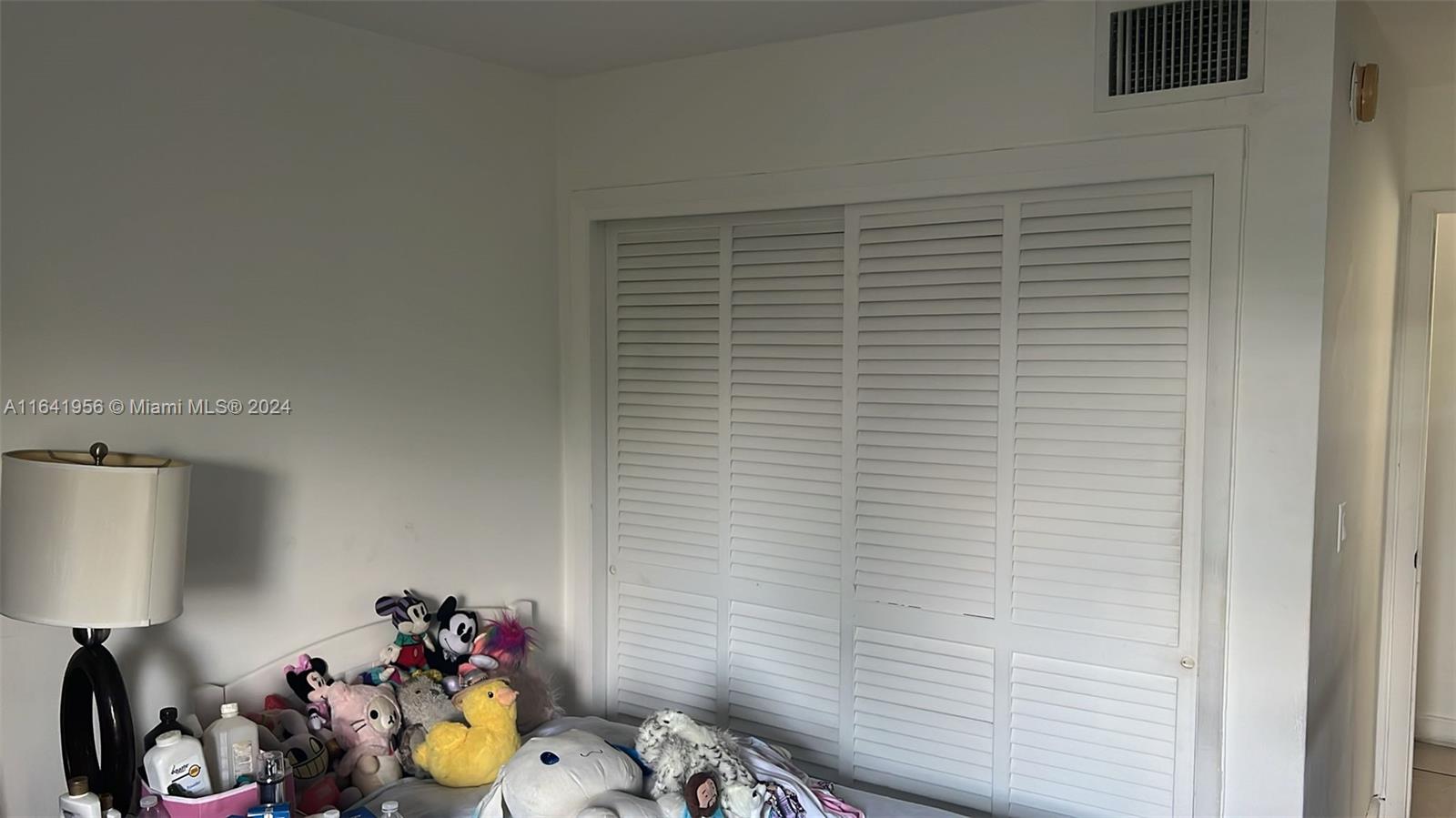 A bedroom features a white louvered closet door and a bed covered with stuffed animals — 7304 SW 82nd St # A210, Miami FL 33143, MIAMI, FL