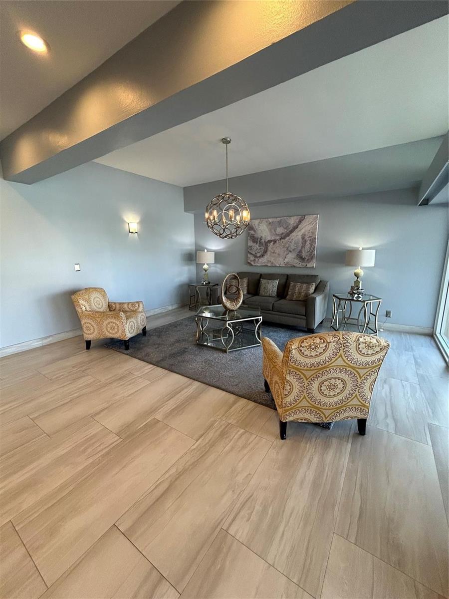 A living room features two patterned armchairs, a grey sofa, and a central chandelier — 1200 Hibiscus Avenue # 702, Pompano Beach FL 33062, POMPANO BEACH, FL