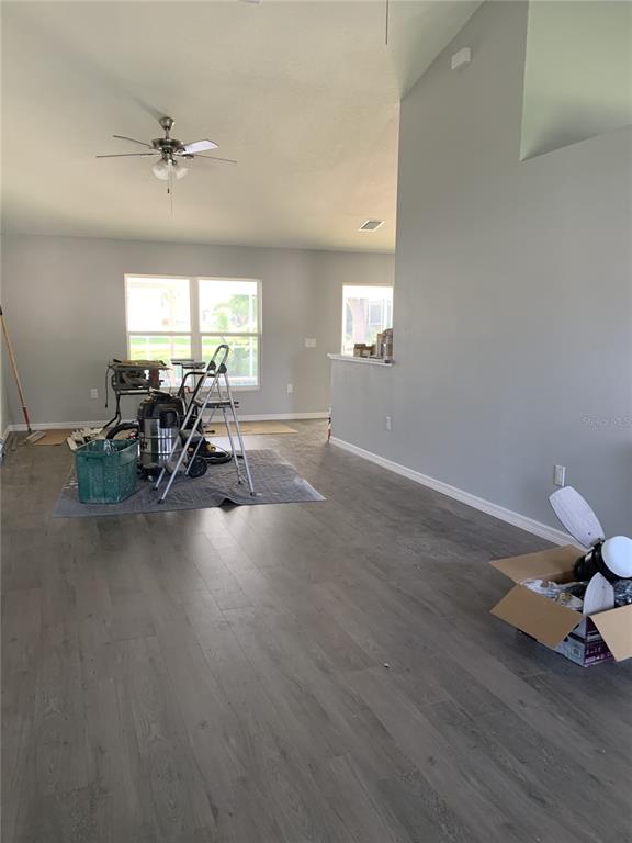 An interior view of a room with gray walls, wood-look flooring, and construction equipment — 11217 ROMAN STREET, SPRING HILL, FL