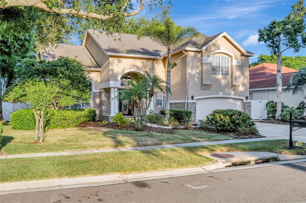 A two-story suburban house with a tan stucco exterior, a garage, and a landscaped yard — 2839 SAFE HARBOR DRIVE, TAMPA, FL