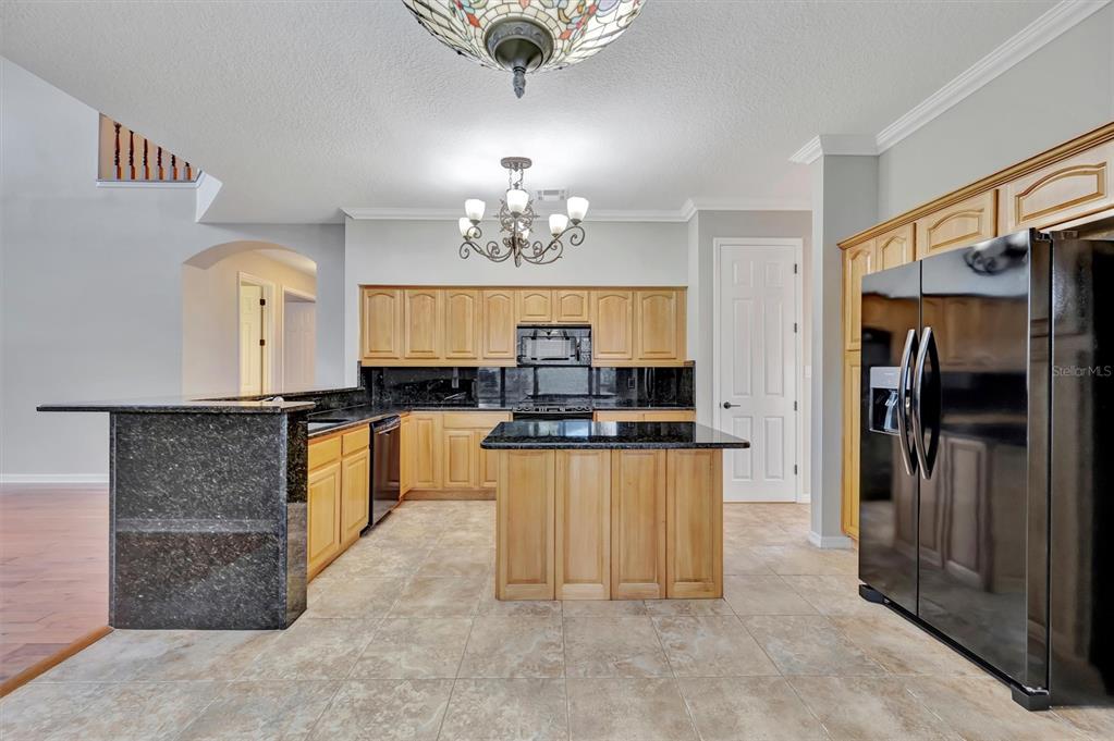 A kitchen features light wood cabinets, black granite countertops, a center island, and tile flooring — 2839 SAFE HARBOR DRIVE, TAMPA, FL