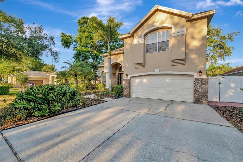 A two-story tan house with a two-car garage and a palm tree in the front yard — 2839 SAFE HARBOR DRIVE, TAMPA, FL