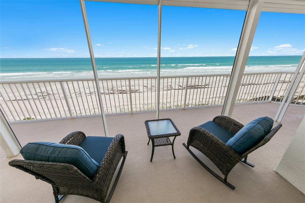 A screened-in balcony with two wicker rocking chairs and a small table overlooking the beach — 4767 S ATLANTIC AVENUE UNIT 402, PONCE INLET, FL