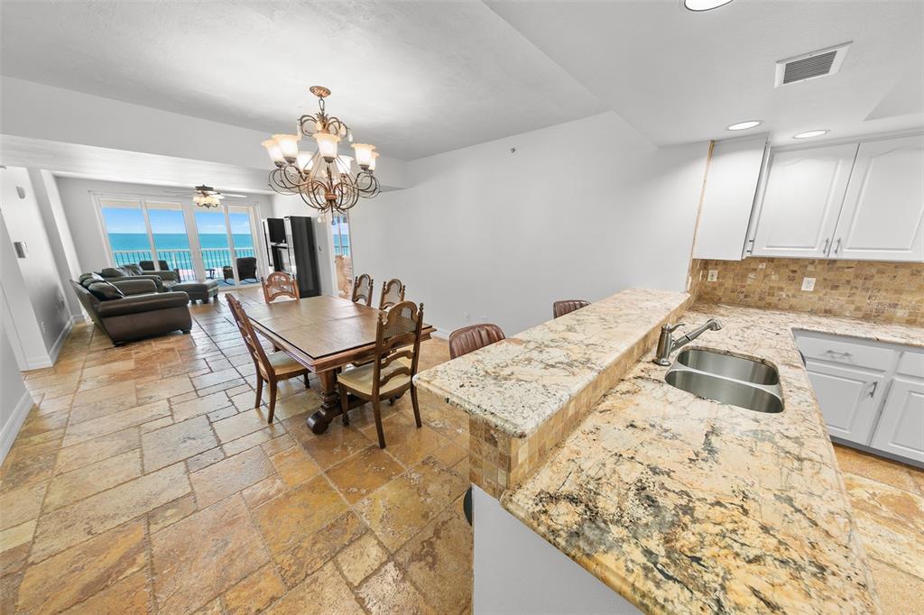 A kitchen with granite countertops overlooks a dining area and living room with ocean views — 4767 S ATLANTIC AVENUE UNIT 402, PONCE INLET, FL